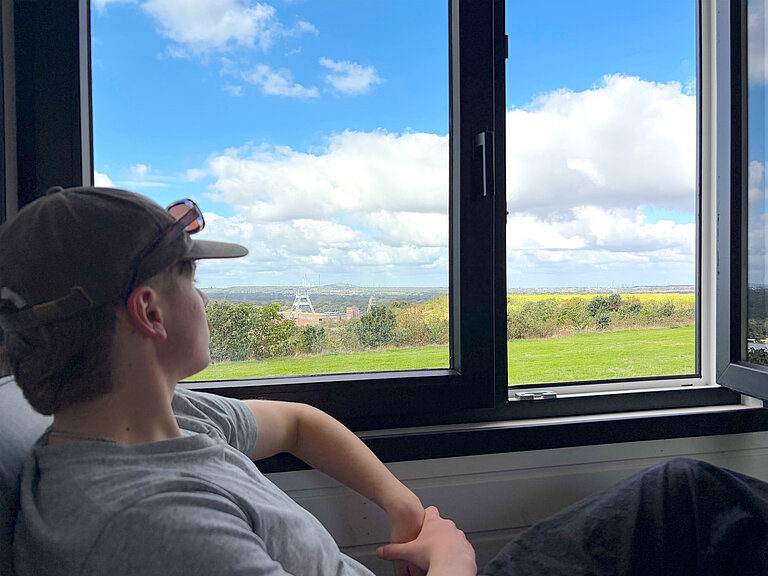 Haldenwärter Fynn blickt ein letztes Mal aus seinem Tiny House auf der Halde Hohenward