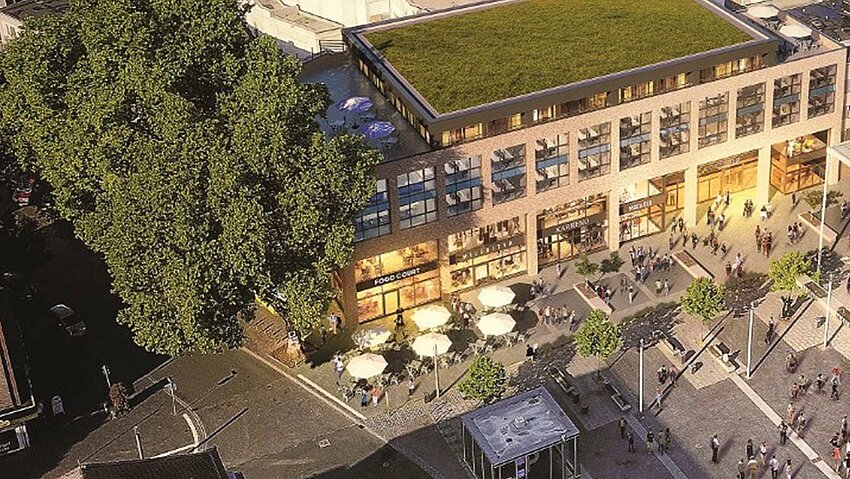 Luftaufnahme des belebten Platzes in Recklinghausen. Ein modernes Gebäude mit begrüntem Dach und Außengastronomie grenzt an den Platz, auf dem sich viele Menschen aufhalten.